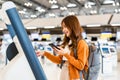 Young Asian woman using self check-in kiosks in airport terminal Royalty Free Stock Photo