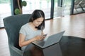 Young asian woman using smartphone and laptop computer working online at home and feel relaxing on armchair Royalty Free Stock Photo