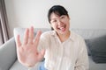Young Asian woman using smartphone for online video conference call with friends waving hand making hello gesture Royalty Free Stock Photo