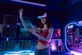 Young Asian woman using virtual reality glasses in the dark room with neon lighting full of computers and technology Royalty Free Stock Photo