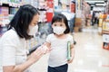Young asian woman wash 2 year old kid hand with alcohal gel in supermarket.