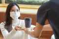 Young Asian woman wear face mask taking a cup of coffee from waiter at cafe Royalty Free Stock Photo