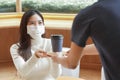 Young Asian woman wear face mask taking a cup of coffee from waiter at cafe Royalty Free Stock Photo