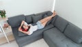 Young Asian woman wear red headphones relaxing and listening the music while using tablet  lying down on couch in living room, Royalty Free Stock Photo