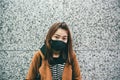 Young asian woman wearing a black mouth mask as her suffers from severe air pollution.
