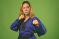 Young Asian woman wearing blue karate Gi against green background