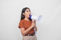 Young Asian woman wearing a brown shirt feeling surprised while shouting and screaming loud using megaphone speaker. Communication Royalty Free Stock Photo
