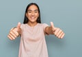 Young asian woman wearing casual clothes approving doing positive gesture with hand, thumbs up smiling and happy for success Royalty Free Stock Photo