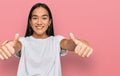Young asian woman wearing casual white t shirt approving doing positive gesture with hand, thumbs up smiling and happy for success Royalty Free Stock Photo