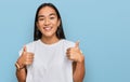 Young asian woman wearing casual white t shirt success sign doing positive gesture with hand, thumbs up smiling and happy Royalty Free Stock Photo