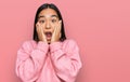 Young asian woman wearing casual winter sweater afraid and shocked, surprise and amazed expression with hands on face Royalty Free Stock Photo