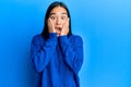 Young asian woman wearing casual winter sweater afraid and shocked, surprise and amazed expression with hands on face Royalty Free Stock Photo