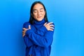Young asian woman wearing casual winter sweater hugging oneself happy and positive, smiling confident Royalty Free Stock Photo