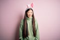 Young asian woman wearing cute easter bunny ears over pink background winking looking at the camera with sexy expression, cheerful Royalty Free Stock Photo