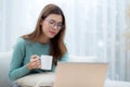 Young asian woman wearing glasses sitting sofa working on laptop computer and drinking coffee in living room. Royalty Free Stock Photo