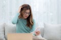 Young asian woman wearing glasses sitting on sofa worried with bills about financial and stress at home. Royalty Free Stock Photo