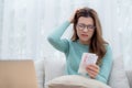 Young asian woman wearing glasses sitting on sofa worried with bills about financial and stress at home. Royalty Free Stock Photo