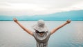 Young asian woman wearing a hat and raising her arms outstretched with lakes and mountains. Happiness and enjoy. Back view of Royalty Free Stock Photo