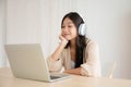 Young asian woman wearing headset while working on computer laptop at house Royalty Free Stock Photo