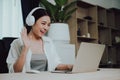 Young asian woman wearing headset while working on computer laptop at house Royalty Free Stock Photo