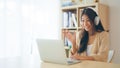 Young asian woman wearing headset while working on computer laptop at house Royalty Free Stock Photo