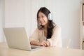 Young asian woman wearing headset while working on computer laptop at house Royalty Free Stock Photo