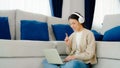 Young asian woman wearing headset while working on computer laptop at house Royalty Free Stock Photo