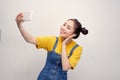 Young Asian woman wearing a jeans dungaree who taking selfie