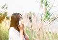 Young asian woman wearing mask and sneezes because of allergy with field at nature