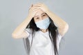 Young Asian woman wearing medical face mask and white t shirt her hand on the head. isolated on gray background,health care