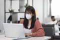 Young Asian woman wearing medical mask working on laptop during remotely work at home. Royalty Free Stock Photo