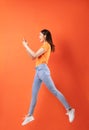 Young asian woman wearing orange T-shirt jumping on orange background Royalty Free Stock Photo