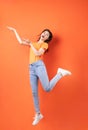 Young asian woman wearing orange T-shirt jumping on orange background Royalty Free Stock Photo