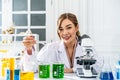 Young asian woman wearing scientist uniform working at scientist laboratory looking at the camera smiling with measuring liquid Royalty Free Stock Photo