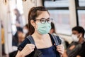 Young Asian woman wearing Surgical face mask against Novel coronavirus or Corona Virus Disease Covid-19 at public subway train. Royalty Free Stock Photo