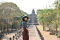 Young asian woman in white hat and striped shirt is exploring the ancient ruins of Prasat Hin Phanom Rung temple in Buriram,