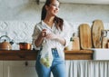 Young asian woman in white shirt hold knitted rag bag shop with green apples in hands on the kitchen