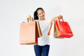 Young asian woman in white t-shirt carrying colorful shopping bags with both arms raised in a ecstatic gesture isolated in white s Royalty Free Stock Photo