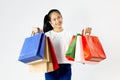 Young asian woman in white t-shirt carrying colorful shopping bags with both arms raised in a ecstatic gesture isolated in white s Royalty Free Stock Photo