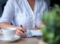 Young Asian woman working from home a hand holding pencil writing agenda note with smartphone, office desk background, Checklist N Royalty Free Stock Photo