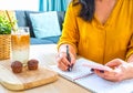 Young Asian woman working from home a hand holding pencil writing agenda note with smartphone, office desk background, Checklist N Royalty Free Stock Photo