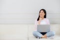 Young asian woman working on laptop computer sitting on sofa in the living room at home. Royalty Free Stock Photo