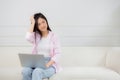 Young asian woman working on laptop computer sitting on sofa in the living room at home. Royalty Free Stock Photo