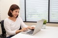 Young Asian woman working with laptop computer on white desk at her condominium. Royalty Free Stock Photo