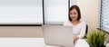 Young Asian woman working with laptop computer on white desk at her condominium. Royalty Free Stock Photo