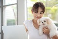 Young Asian woman working on laptop beside her dog chihuahua feeling happiness work form home