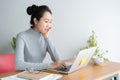 Young asian woman working on laptop in the home office desk, And sit at table resting chin on hand Royalty Free Stock Photo