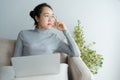 Young asian woman working on laptop in the home  And sit at sofa resting chin on hand. Royalty Free Stock Photo