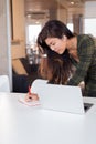 Concentrated female worker writing in planner