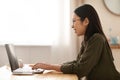 Young asian woman working online, using laptop at kitchen Royalty Free Stock Photo